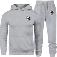 Ensemble jogging Dragon Ball Z composé d’un sweat à capuche gris clair et d’un pantalon assorti, ornés du symbole japonais "悟". Une tenue élégante et confortable idéale pour les fans de manga et d’anime.