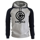 Sweat à capuche bicolore avec un corps gris clair et des manches navy, arborant un logo Capsule Corp noir centré sur le devant. Ce hoodie présente des cordons noirs assortis et une coupe moderne pour un confort optimal, idéal pour les amateurs de mode casual et de culture pop.


