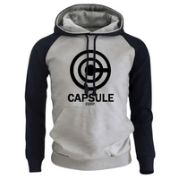 Sweat à capuche bicolore avec un corps gris clair et des manches navy, arborant un logo Capsule Corp noir centré sur le devant. Ce hoodie présente des cordons noirs assortis et une coupe moderne pour un confort optimal, idéal pour les amateurs de mode casual et de culture pop.

