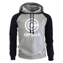 Sweat à capuche bicolore avec un corps gris clair et des manches navy contrastantes, orné du logo blanc Capsule Corp sur le devant. Le hoodie comporte une poche kangourou pratique et des cordons assortis noirs pour un look moderne et confortable, parfait pour les amateurs de mode geek.