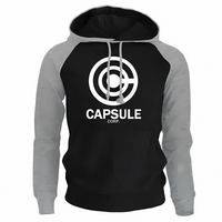 Sweat à capuche bicolore noir avec manches grises, affichant le logo blanc de Capsule Corp sur le devant. Doté de cordons gris et d'une coupe confortable, ce hoodie est parfait pour les fans d'animés et de streetwear moderne.