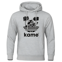 Sweat à capuche gris clair avec logo noir représentant la maison de Kame (Tortue Géniale) entourée de palmiers, design minimaliste inspiré de l'univers Dragon Ball, idéal pour un look casual et geek.