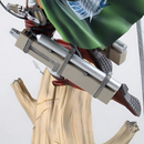 Détail de l'équipement de manœuvre tridimensionnel de Levi sur sa figurine, incluant les bottes, les lames et le harnais attaché à un tronc d'arbre