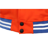 Détail de la veste Teddy Dragon Ball avec boutons noirs et bords-côtes bleus et orange.